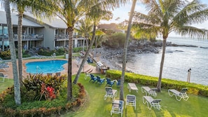 A resort with a pool, lounge chairs, and a view of the ocean.
