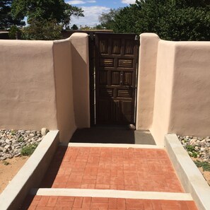 Enter through the traditional door, flanked by a paved pathway and a low wall.