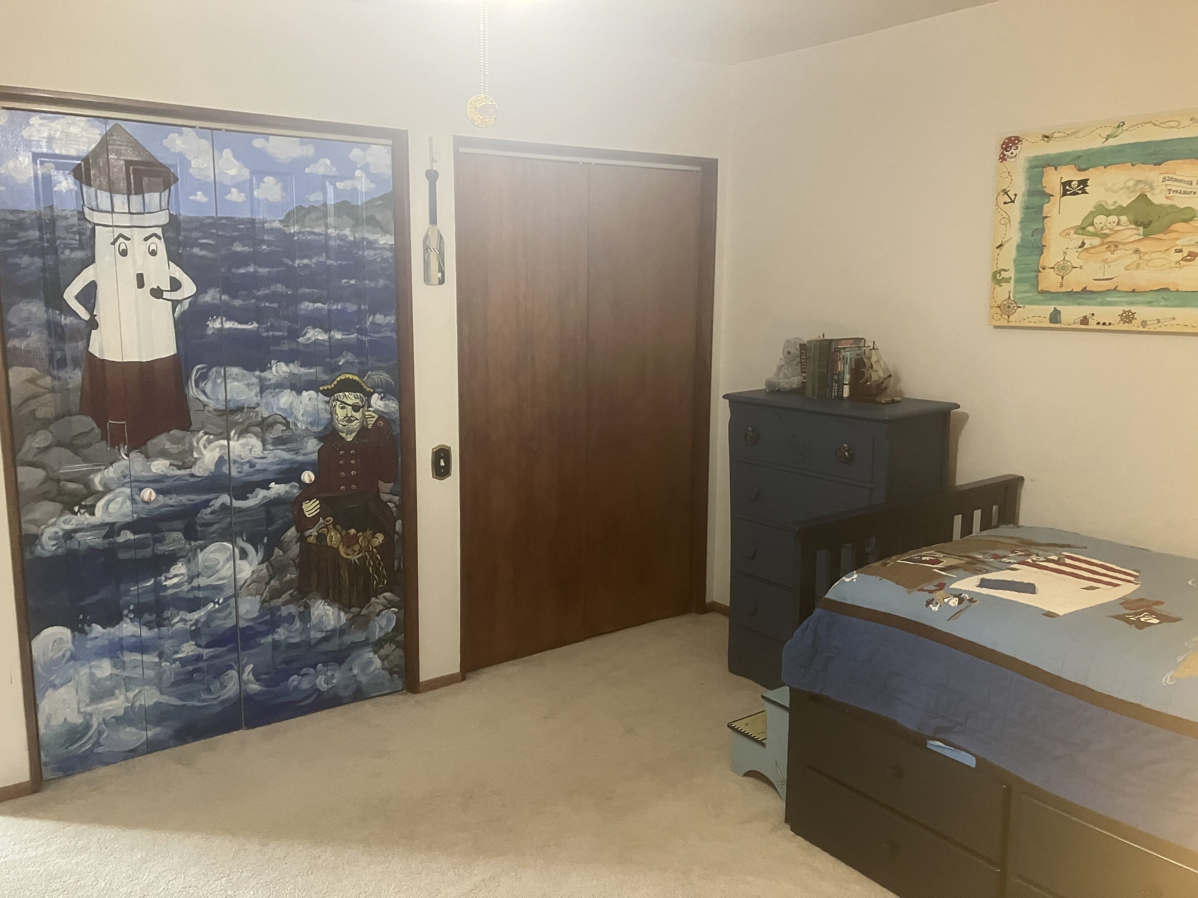 A room with a wooden door, a blue cabinet, and a bed with a patterned bedspread.