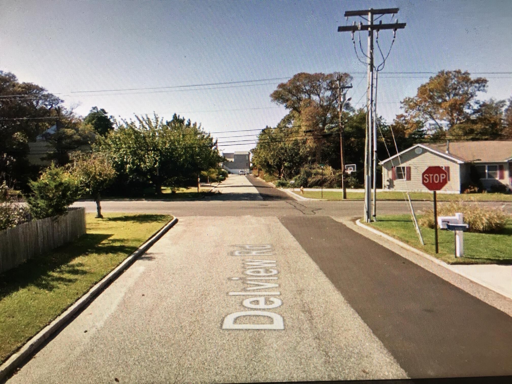 A residential street with a STOP sign, a mailbox, and a house in the background.