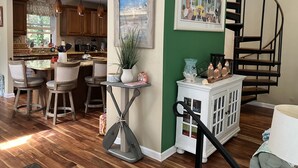 A modern kitchen with wooden cabinets, a dining area with bar stools, a staircase, and a view of the outdoors. - Mountain House at the Beach! Dog Friendly, Short Walk to the Beach. (Villas)