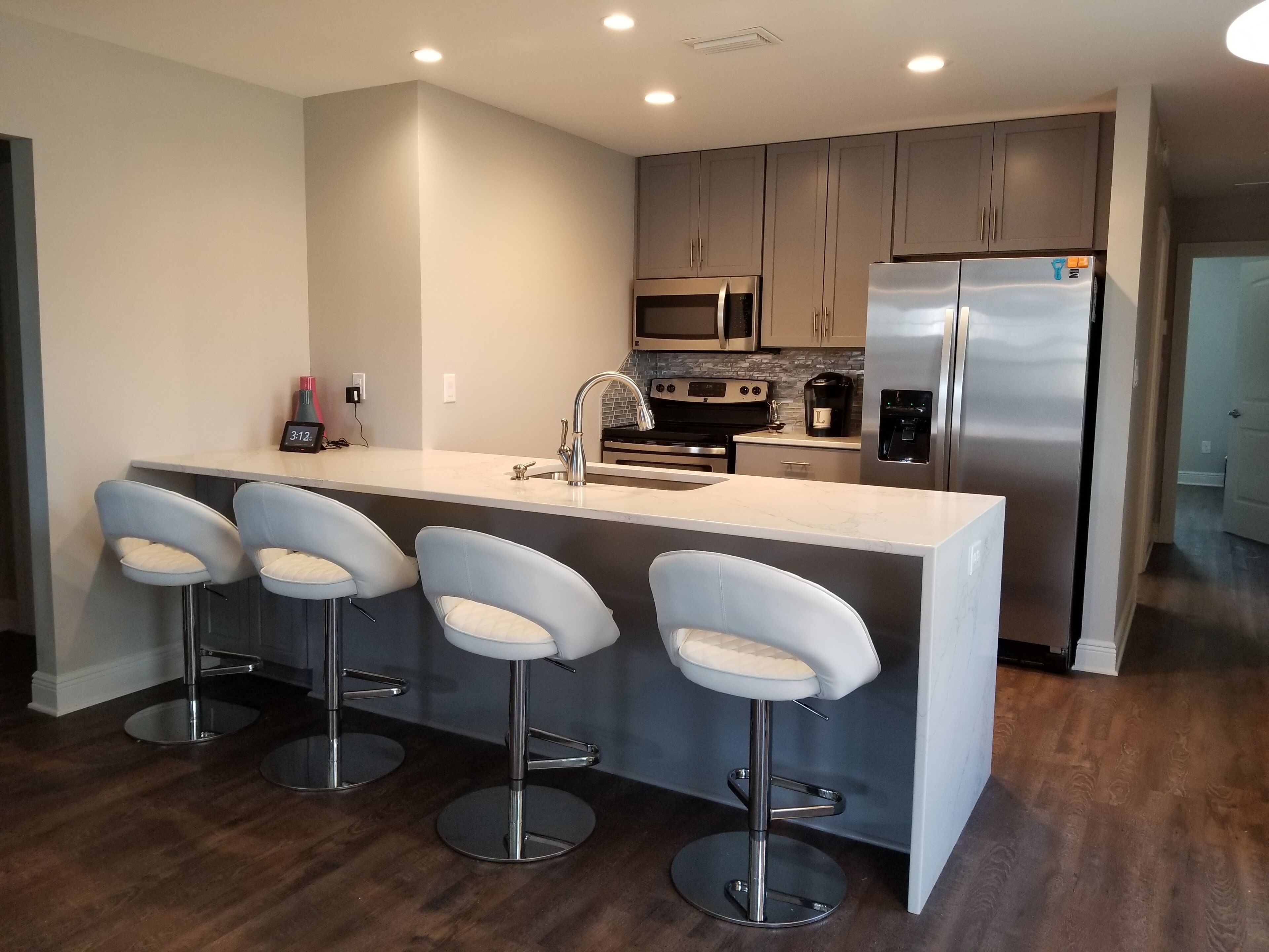 A modern kitchen with a central island, stainless steel appliances, and bar stools.