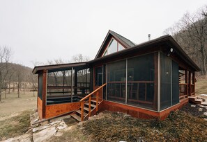 A cabin with a large glass window, wooden exterior, and a staircase leading to the entrance. - Secluded Rustic-Modern Log Cabin w/ Hot Tub, Private Creekside Escape (Ferryville)