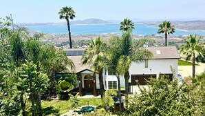 Ein Haus mit Pool, umgeben von Palmen und Blick auf ein großes Gewässer.