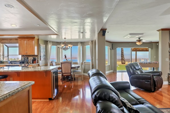 A spacious living area with a leather sofa, a dining table with chairs, and a kitchen area with wooden cabinets and a granite countertop. - Highest reviewed property in the area - best view of  your life! (Lake Mathews)