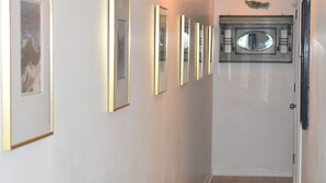 A hallway with framed mirrors on the wall and a door at the end. - Oceanfront Heaven in Exclusive West End, Ocean Isle Beach, NC  (Ocean Isle Beach)