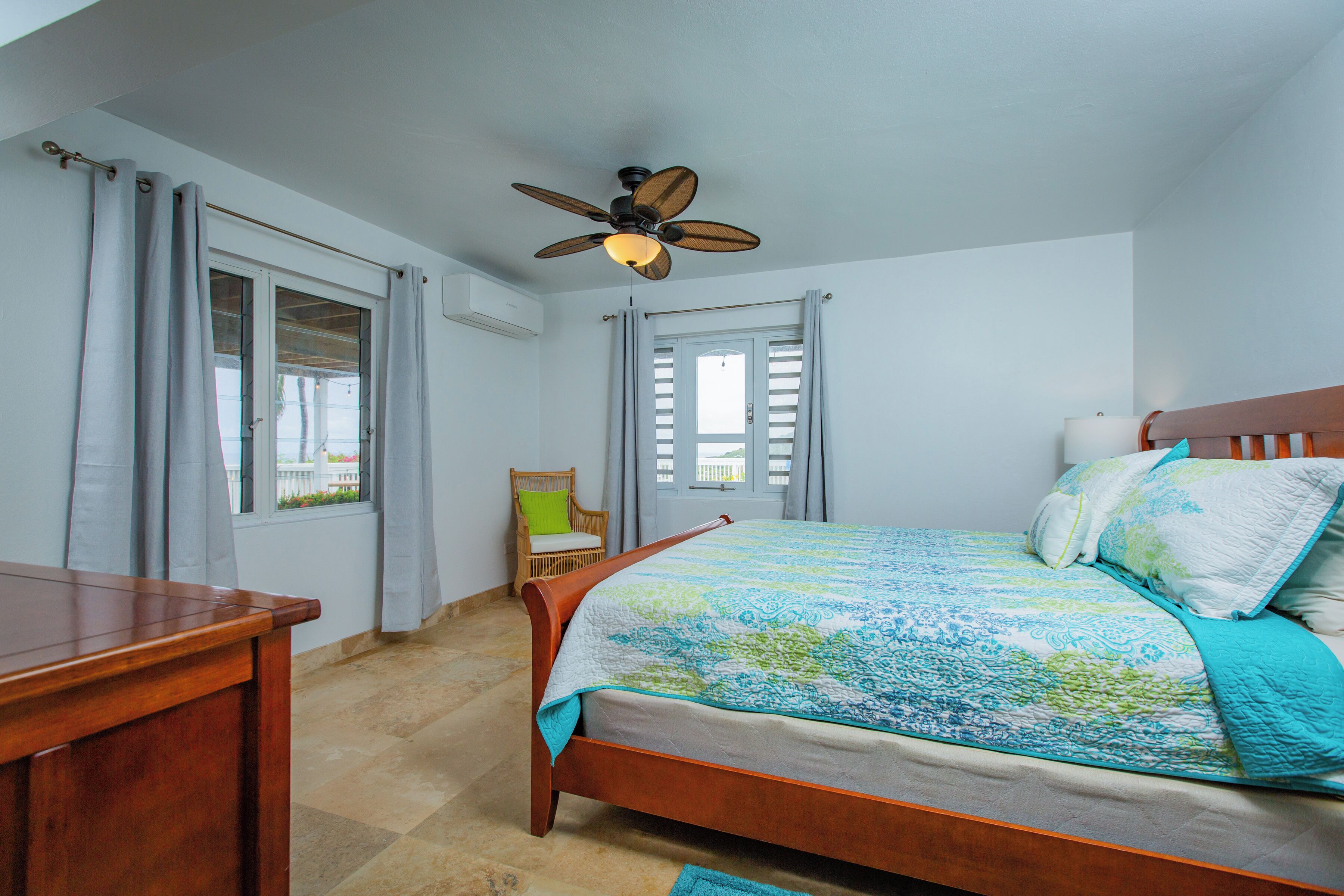 A bedroom with a wooden bed, a ceiling fan, and a window with curtains.