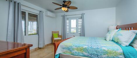A bedroom with a wooden bed, a ceiling fan, and a window with curtains.