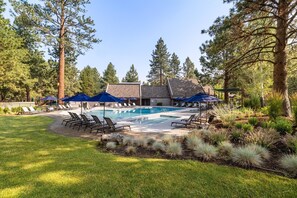 Relax by the serene pool surrounded by lush greenery and tall pine trees.