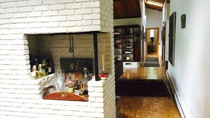 A room with a brick fireplace, wooden flooring, and a bookshelf. - Secluded Getaway: Bear Mt, Cold Spring, Beacon, West Point!   (Garrison)