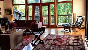 A spacious living room with a wooden ceiling, large windows, a fireplace, and a cozy seating area. - Secluded Getaway: Bear Mt, Cold Spring, Beacon, West Point!   (Garrison)