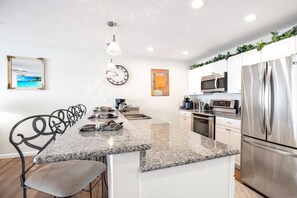 Enjoy cooking in the well-equipped kitchen with a central island, stainless steel appliances, and a dining area with a table and chairs.