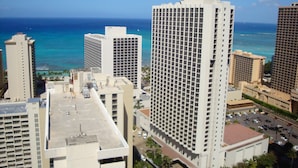 A high-rise hotel with a view of the ocean, featuring a grid of windows and a flat roof. - Amazing views of Diamond Head, Waikiki Beach, and the Pacific Ocean! (Honolulu)