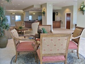 Guests can relax in the hotel's central seating area, surrounded by comfortable chairs and a large potted plant.