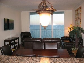 Enjoy ocean views from the comfort of this stylish living room, featuring a sofa, dining table, and TV.