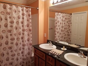 A bathroom with two sinks, a mirror, and a shower curtain with a shell pattern. - Winter Paradise on the St. Johns River w/deep water boat slip (Welaka)