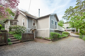 A two-story house with a front porch, a chimney, and a gravel driveway. - Downtown home, large deck, short walk to the heart of Hood River! Pet Friendly! (Hood River)