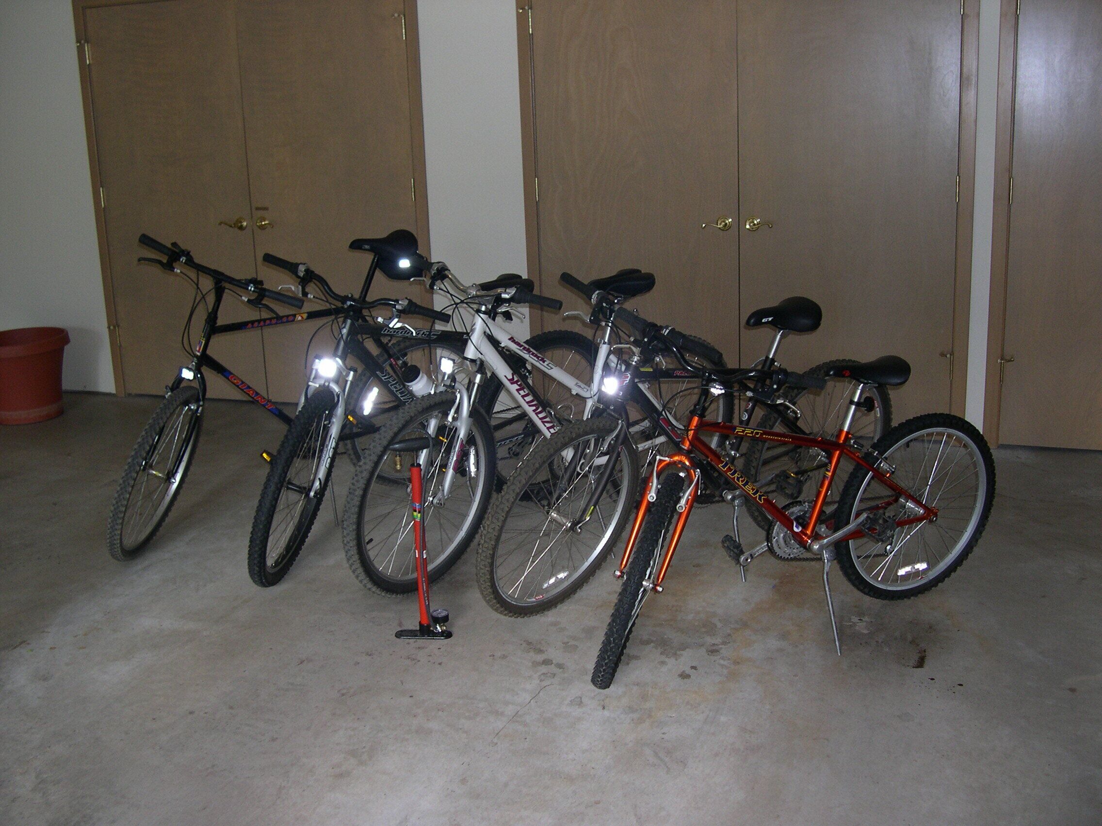 Bicicletas estacionadas en el interior, con piso de concreto y puertas de madera al fondo.