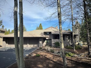 A two-story house with a garage, surrounded by trees and a well-maintained lawn.