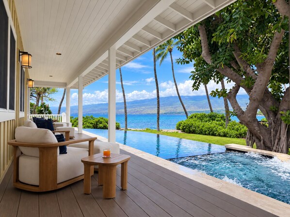 A covered outdoor area with a pool, seating, and a view of the ocean.