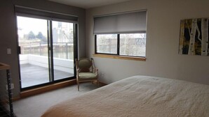 A bedroom with a large bed, a chair, a window with a view, and a balcony. - Waterfront Pearl Home Away from Home (Portland)