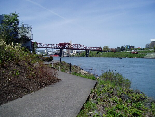 A riverside walkway with a metal bridge in the background. - Waterfront Pearl Home Away from Home (Portland)
