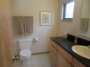 A bathroom with a toilet, two towels, a framed picture, a sink, and a window. - Waterfront Pearl Home Away from Home (Portland)