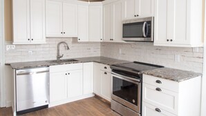 A kitchen with white cabinets, a stainless steel dishwasher, a microwave, and a stove. - Short walk to the Beach, sleeps 8, four bedrooms, private patio, 2026 weeks open (Cape May)