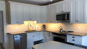 A kitchen with white cabinets, a stainless steel dishwasher, a microwave, and a gas stove. - Short walk to the Beach, sleeps 8, four bedrooms, private patio, 2026 weeks open (Cape May)