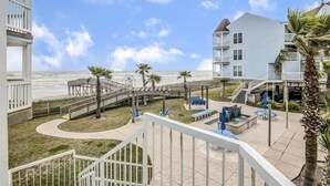 A beachfront hotel with a pool area, a wooden deck, and a view of the ocean. - "Beachfront Paradise - Wake Up to Ocean Views & Waves! (Galveston)