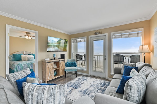 A living room with a sofa, chairs, a coffee table, a TV, a ceiling fan, and a view through the glass doors. - "Beachfront Paradise - Wake Up to Ocean Views & Waves! (Galveston)