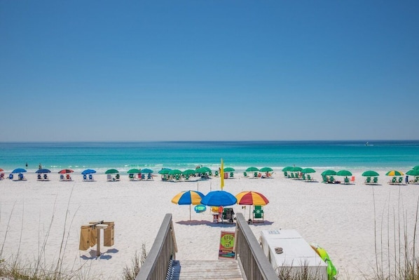 Enjoy a leisurely day at the beach with comfortable seating and shade under colorful umbrellas.