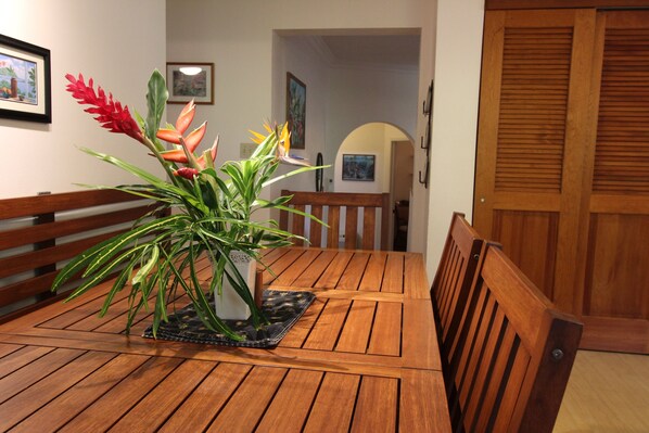 A wooden dining table with a potted plant in the center.