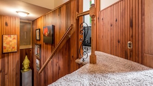 A wooden-paneled hallway with a carpeted staircase, a Buddha statue, and framed artwork. - The Highlands Hangout, EXPO, DOWNTOWN, restaurant row!!!  Game room & LOCATION! (Louisville)