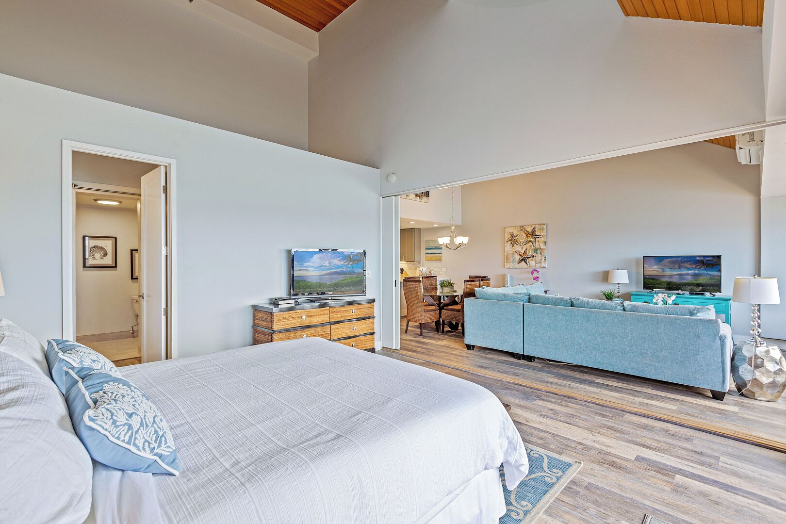 A spacious bedroom with a large bed, a dresser, and a television in the living area.