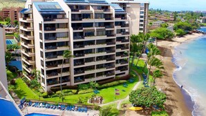 A multi-story hotel with balconies, a pool, and a beachside location.