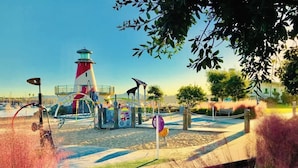 A park with a lighthouse, playground, and a bench.