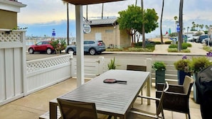 An outdoor patio with a table and chairs, a view of the street, and a building with a sign.