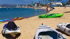 A beach with kayaks and a lighthouse in the background.