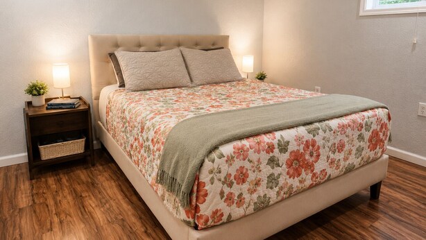 Une chambre à coucher avec un lit, des tables de chevet, une lampe, une petite plante et une fenêtre.