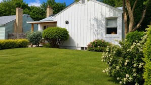 Une maison de plain-pied avec un porche à l’avant, une cheminée et une pelouse bien entretenue.