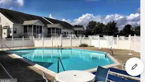 A swimming pool with lounge chairs and a covered area with windows. -     🏖️ Check out our off season discounted rates.  (Lewes)