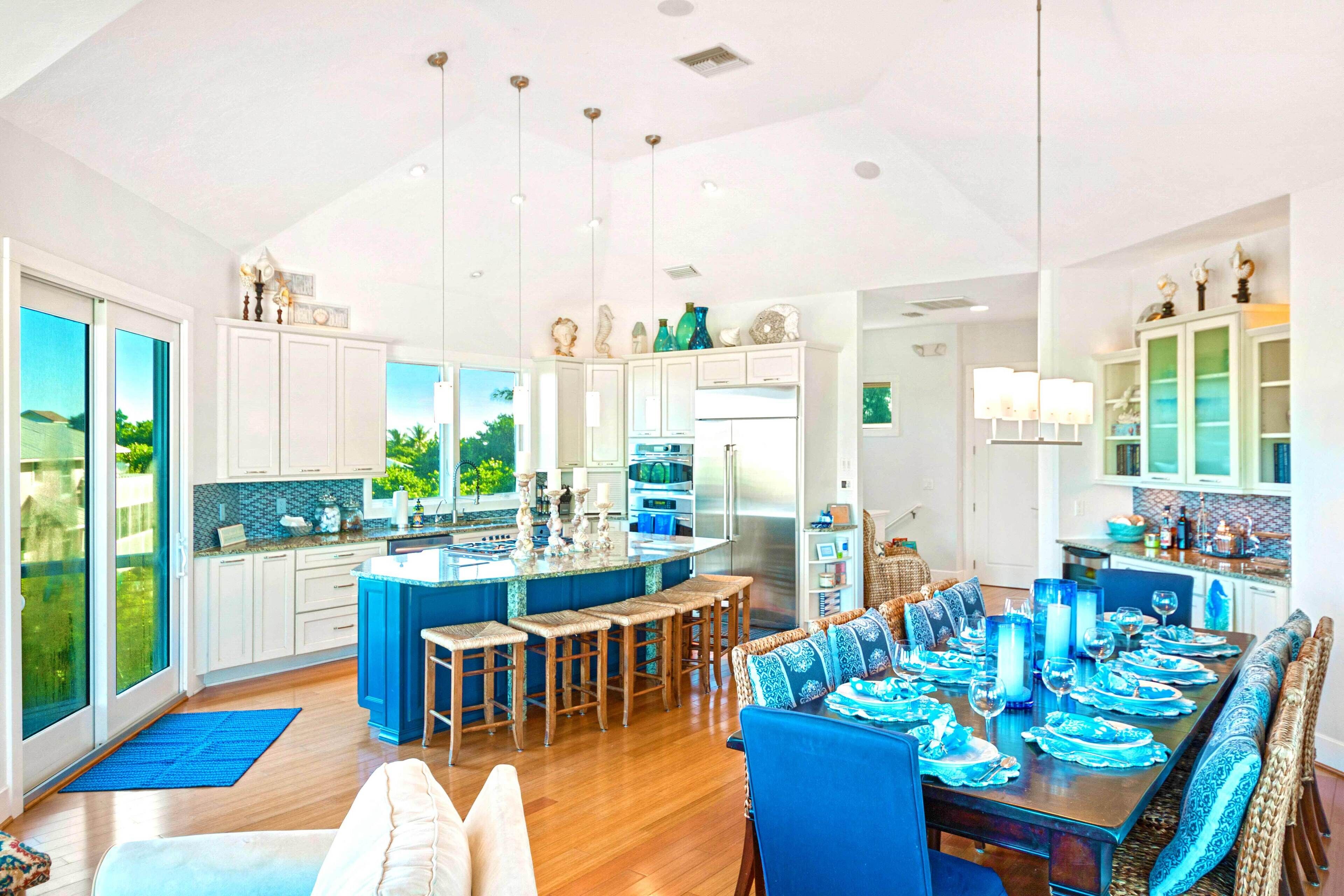 Una cocina amplia con una isla central, armarios blancos y vistas al exterior.
