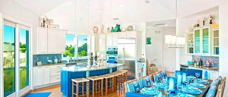 Una cocina amplia con una isla central, armarios blancos y vistas al exterior.