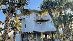 A two-story house with a balcony, surrounded by palm trees and a well-maintained garden.