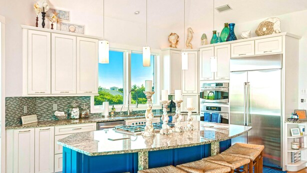 A spacious kitchen with a large island, white cabinetry, and a view of the outdoors.