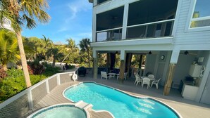 A swimming pool with a hot tub, surrounded by a wooden deck and outdoor furniture.