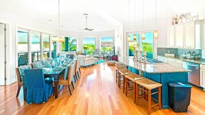 A spacious kitchen with a large island, wooden flooring, and a view of the outdoors.