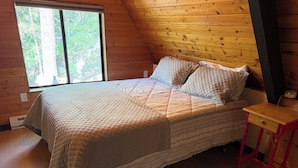 Ein Schlafzimmer mit einem Bett, einem Fenster und einem kleinen Holztisch.