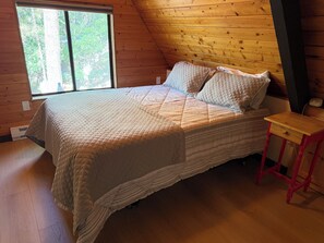 Ein Schlafzimmer mit einem Bett, einem Fenster und einem kleinen Holztisch.